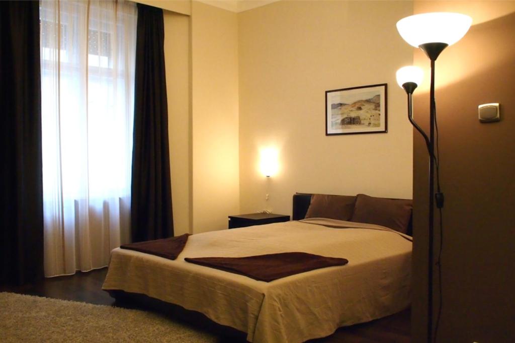 a bedroom with a bed and a lamp and a window at Budapest Suites in Budapest