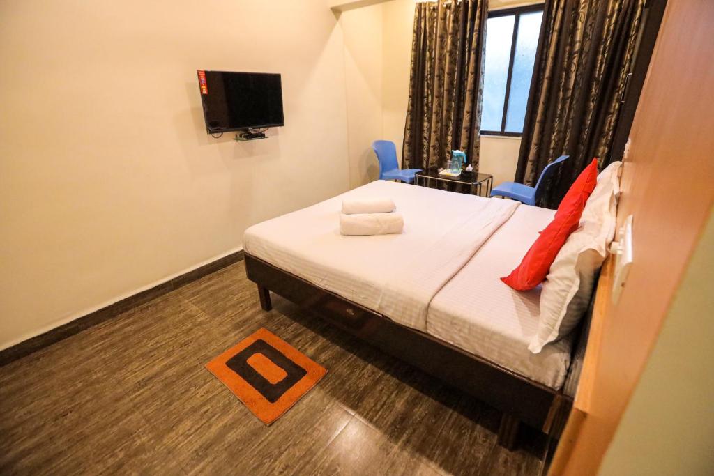 a bedroom with a bed and two chairs and a television at Hotel Sai Niwas in Lonavala