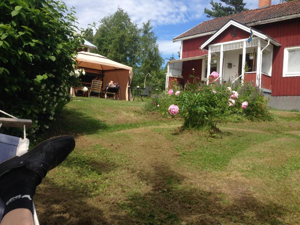 a person sitting on a bench in front of a red house at Tömsagården in Järvsö