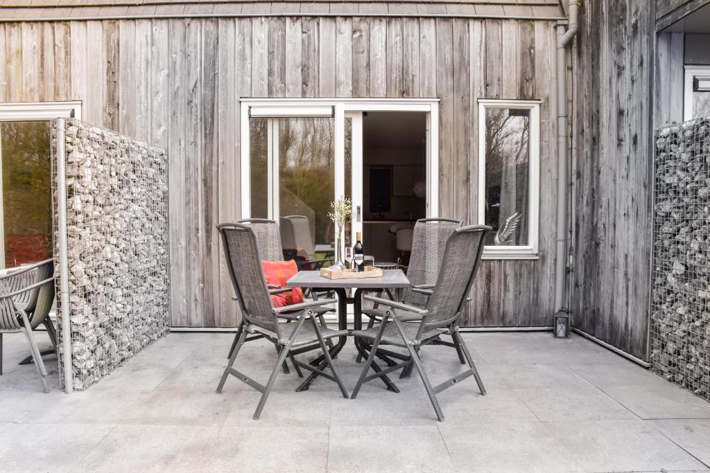 een eetkamer met een tafel en stoelen op een patio bij Wyn 72 in Hollum