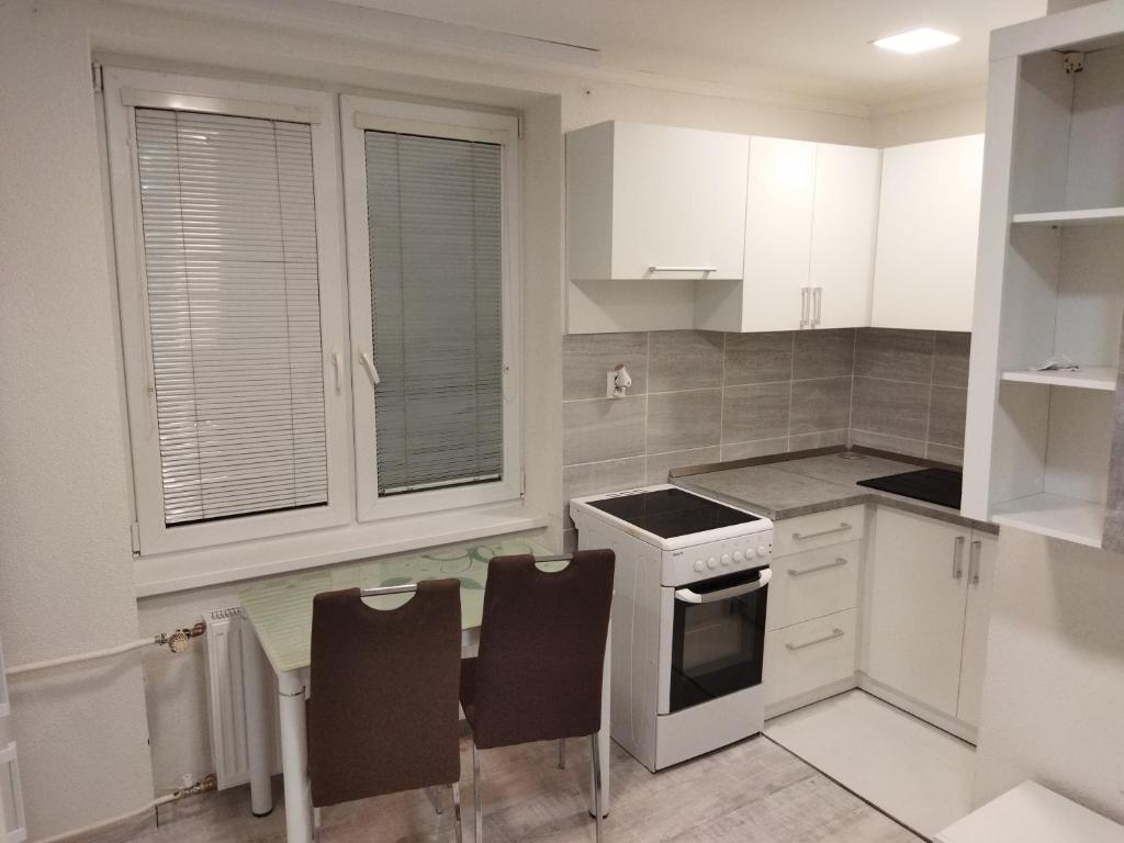 uma cozinha com armários brancos e uma mesa e cadeiras em Apartmán blízko centra em Humenné