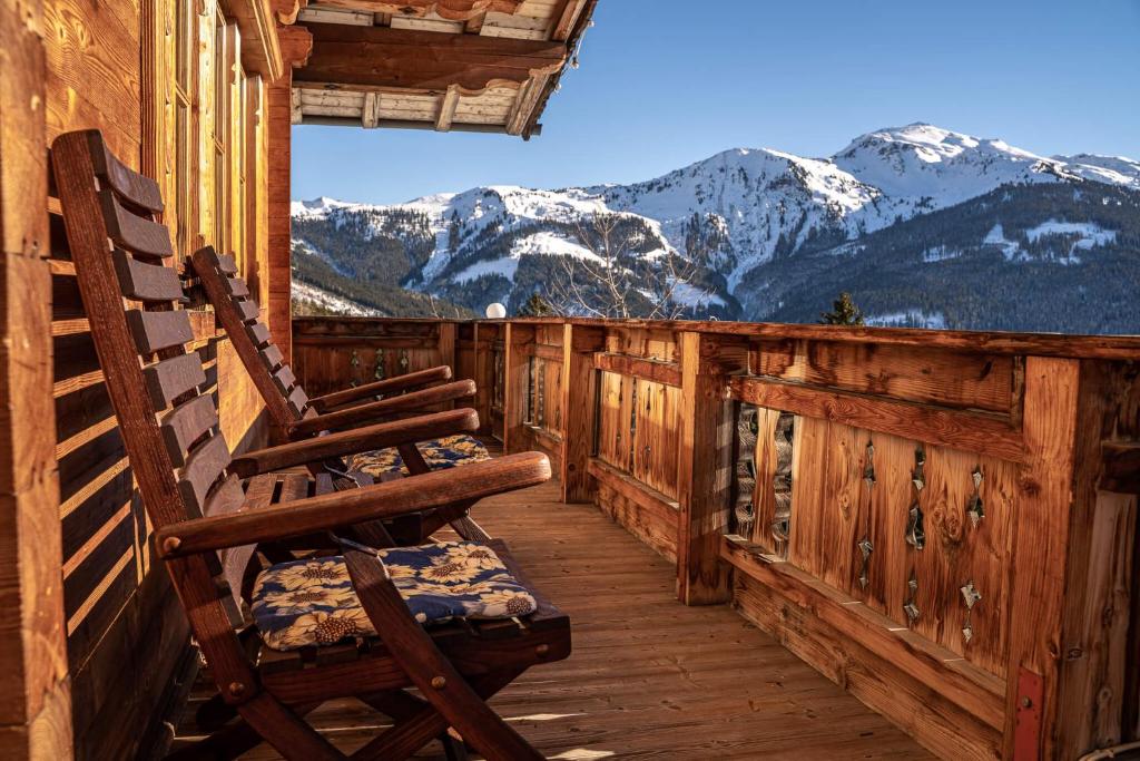 una sedia a dondolo sul portico di una cabina con montagne di Ferienhaus Haus Gilfert a Pill