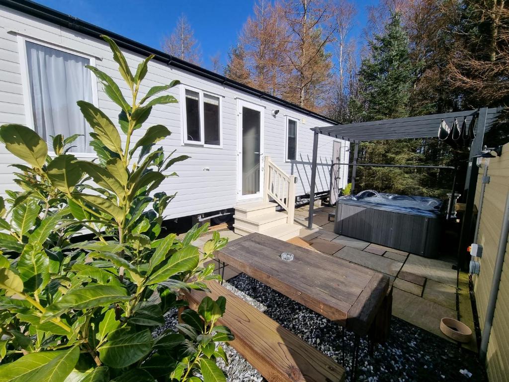 a tiny house with a deck and a bench at Cheviot Pines Hot tub in Swarland