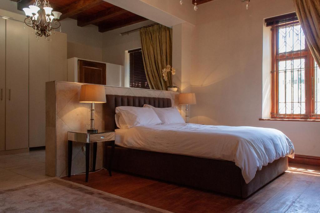 a bedroom with a large bed and a lamp at Bloemendal Wine Estate Accommodation in Cape Town