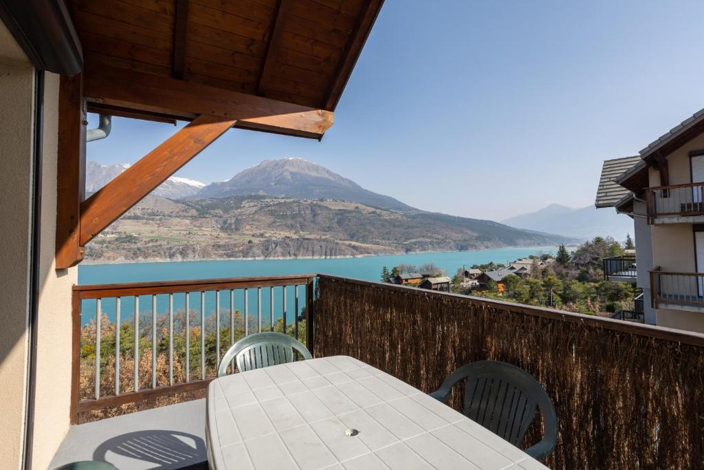 a table on a balcony with a view of a mountain at Le Bleuet du Lac in Savines