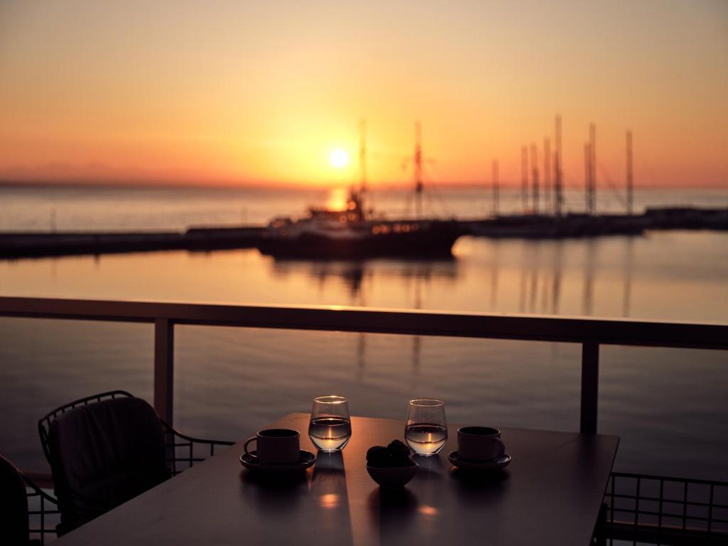 a table with two glasses of wine and a boat at Monopolio Waterfront Apartment Zakynthos in Zakynthos