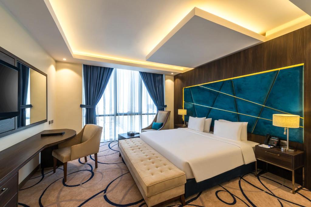 リヤドにあるWarwick Riyadh Al Wezaratの大きなベッドとデスクが備わるホテルルームです。