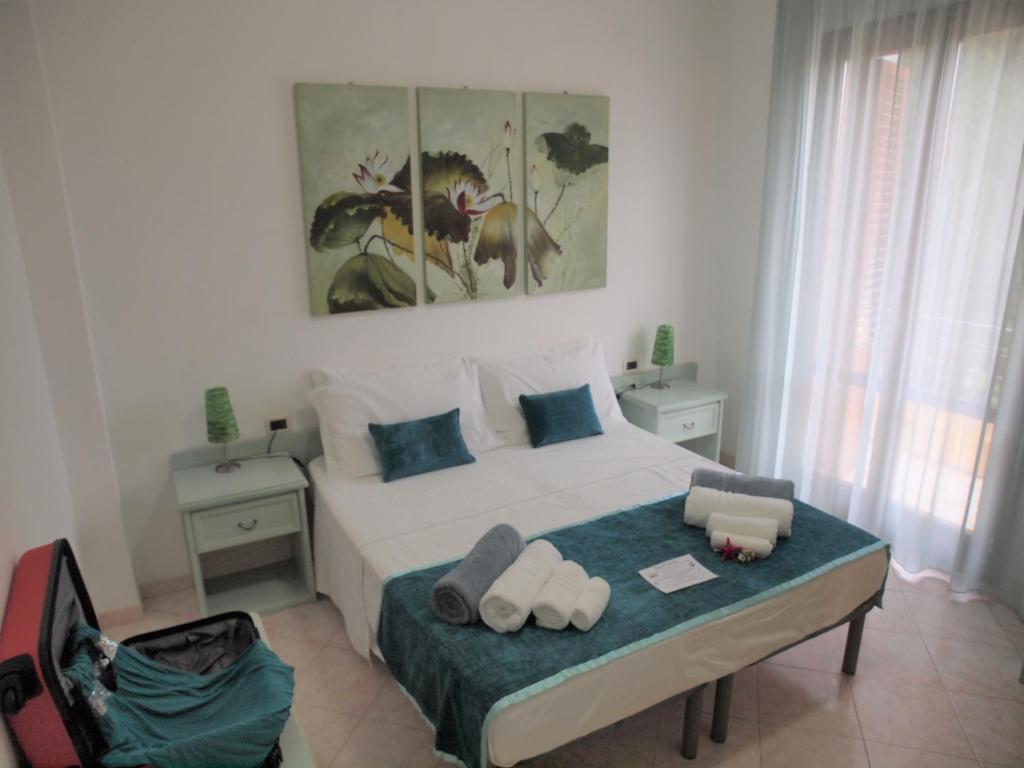 a bedroom with a large white bed with blue pillows at Locanda Lighea Rooms in San Vito lo Capo