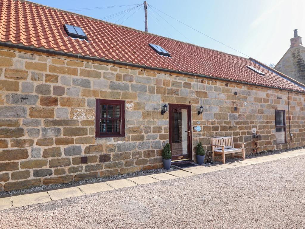 a brick building with a chair and a door at The Old Dairy, Ellerby in Saltburn-by-the-Sea