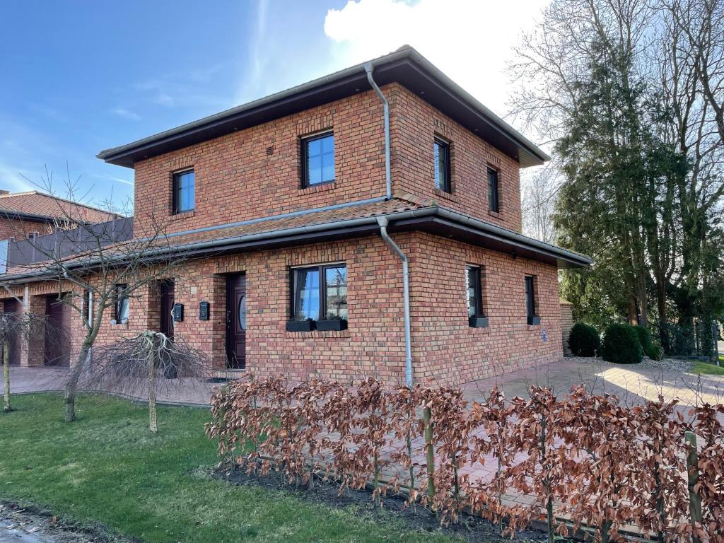 une maison en briques avec une clôture devant elle dans l'établissement Zum Herold II, à Aurich