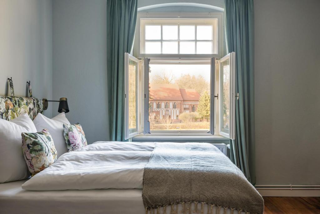 ein Schlafzimmer mit einem Bett und einem großen Fenster in der Unterkunft Klostergartenhotel Marienfließ in Stepenitz