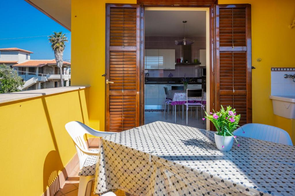 una mesa de comedor en un balcón con una pared amarilla en House Pantanello Beach - SiciliaVacanza, en Avola