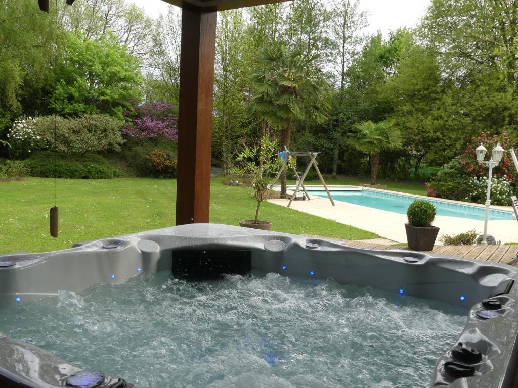 uma banheira cheia de água em frente a uma piscina em Residence Labrège T2Duplex Spa Piscine em Sargé Les Le Mans 