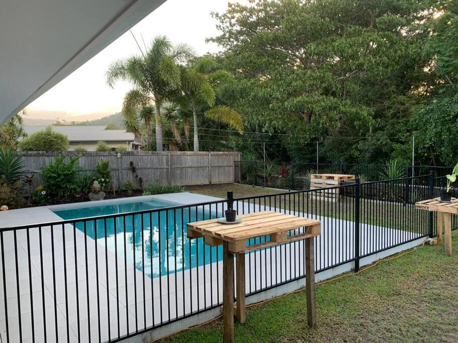 uma mesa de madeira ao lado de uma piscina em Beautiful large home available in tropical north Queensland em Port Douglas