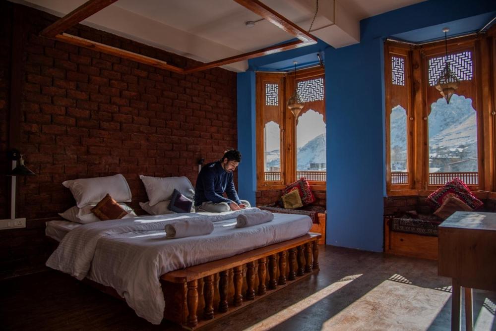 een man op een bed in een kamer bij Black Sheep Bed & Breakfast in Kargil