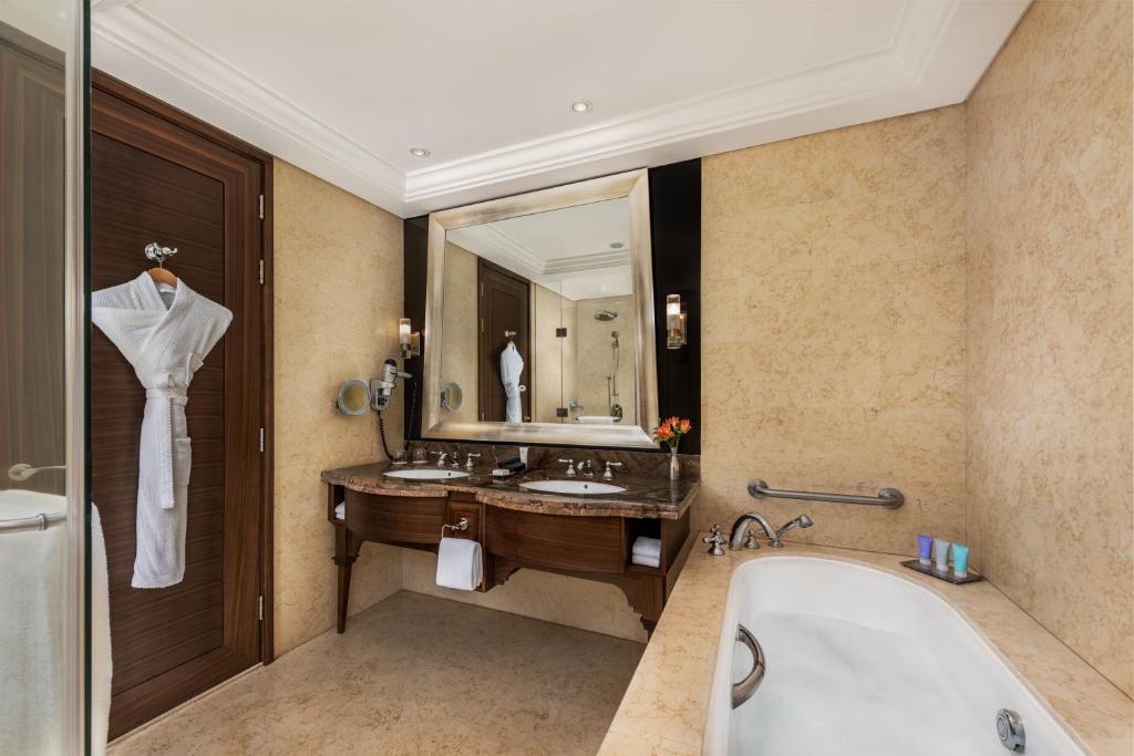 a bathroom with a tub, sink and mirror at Dusit Thani Abu Dhabi in Abu Dhabi