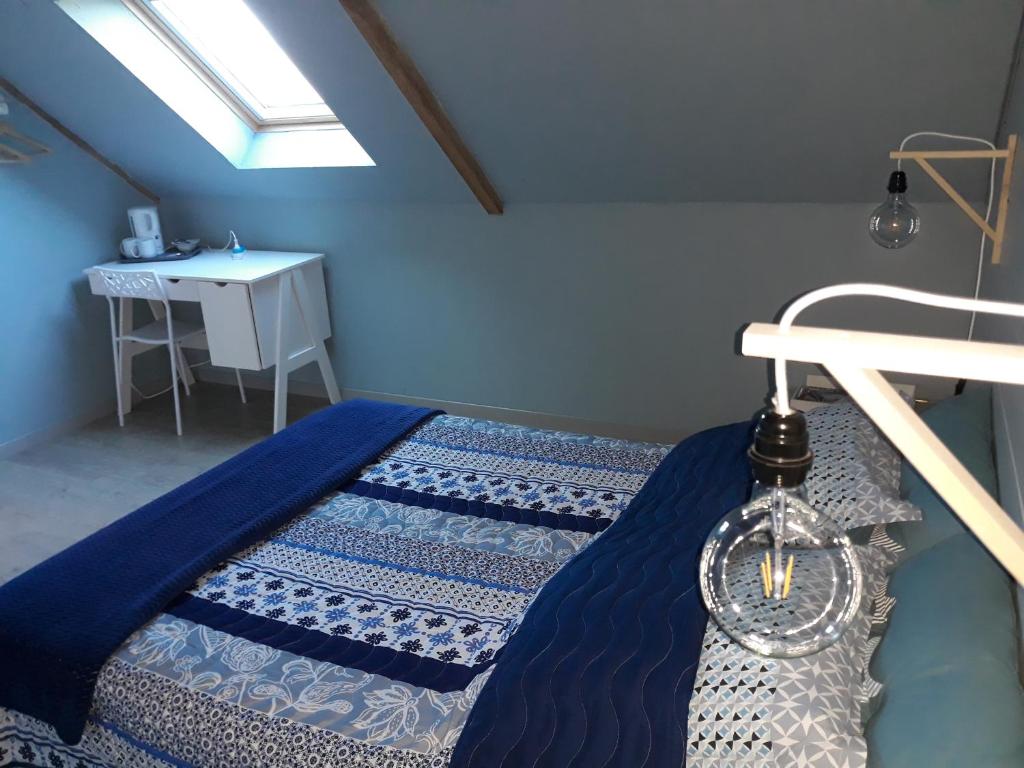 Un dormitorio con una cama con sábanas azules y una mesa. en Au Ker Lauriers chambres et table d Hôtes en Saint-Denoual