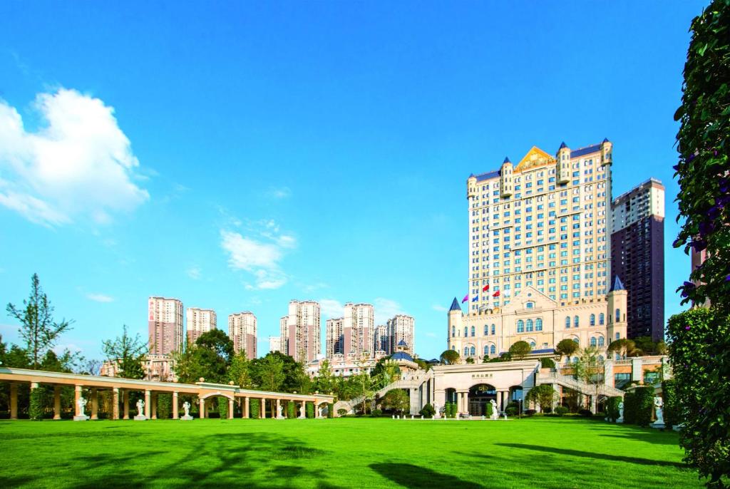 een groen park tegenover een stad met hoge gebouwen bij Wyndham Grand Kunming East in Kunming