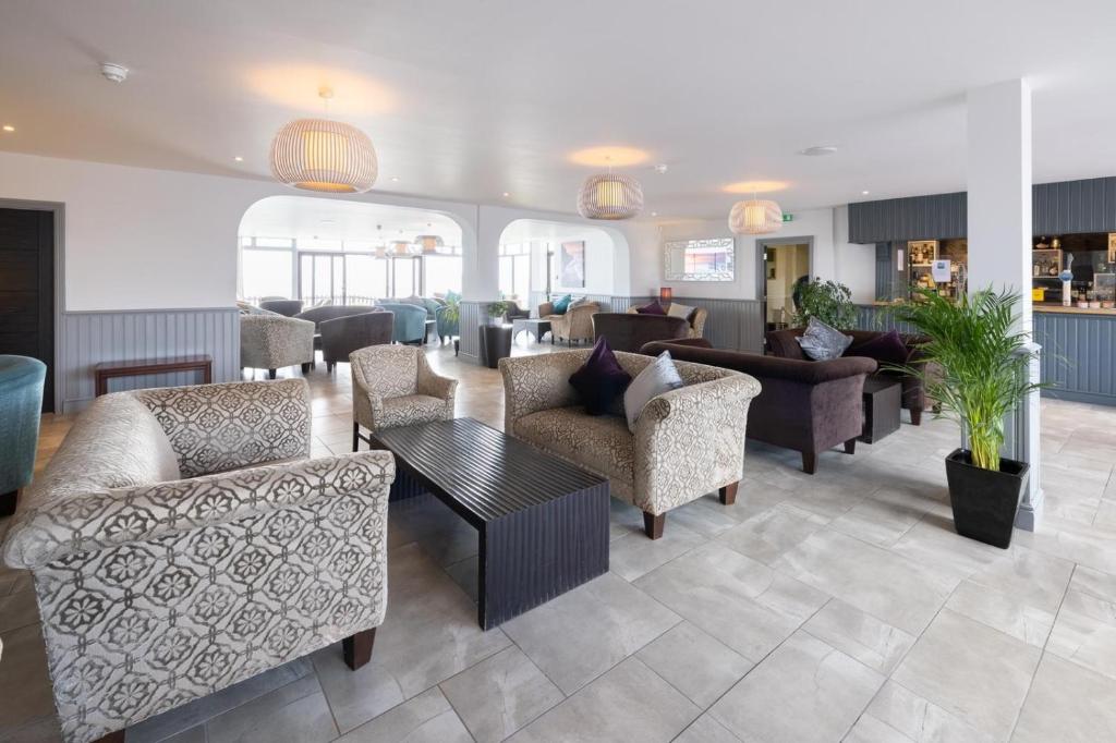 a living room with couches and chairs and tables at The Pines Hotel in Swanage