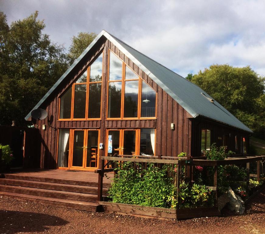 a large wooden house with glass windows and stairs at Bonnie Haven in Lochinver