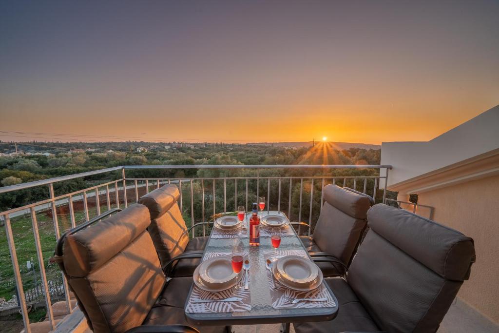 una mesa y sillas en un balcón con puesta de sol en Mimoza's Apartment, en Cefalonia