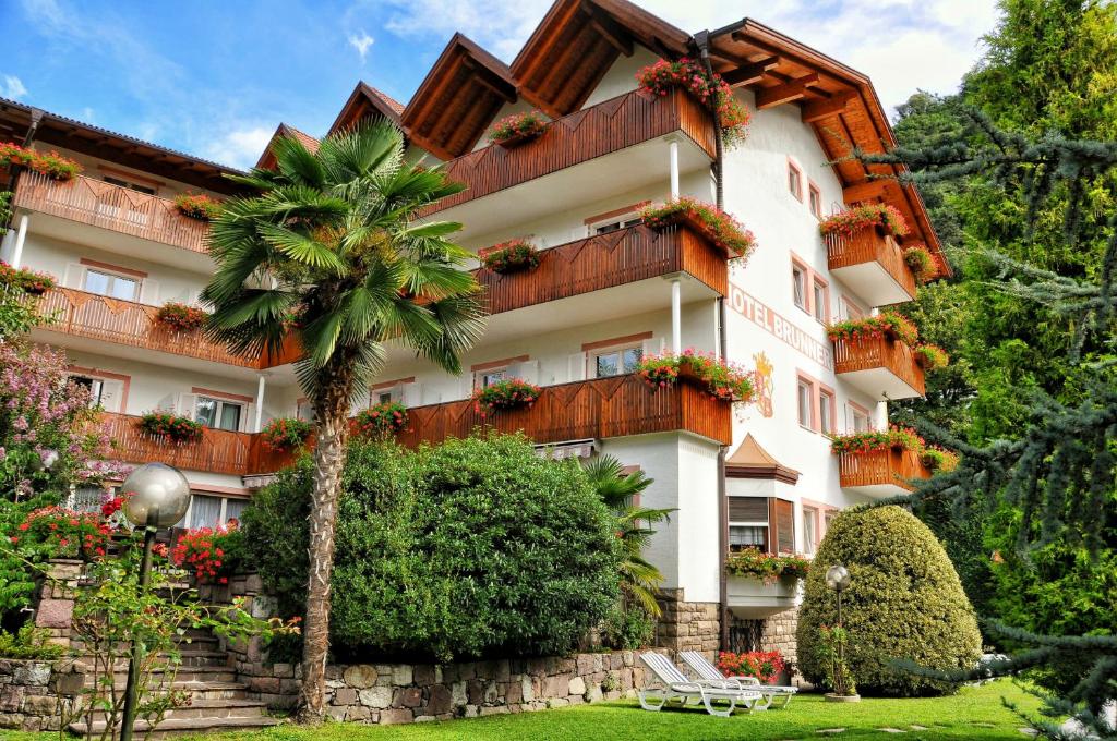 um edifício com uma palmeira em frente em Hotel Brunner em Merano