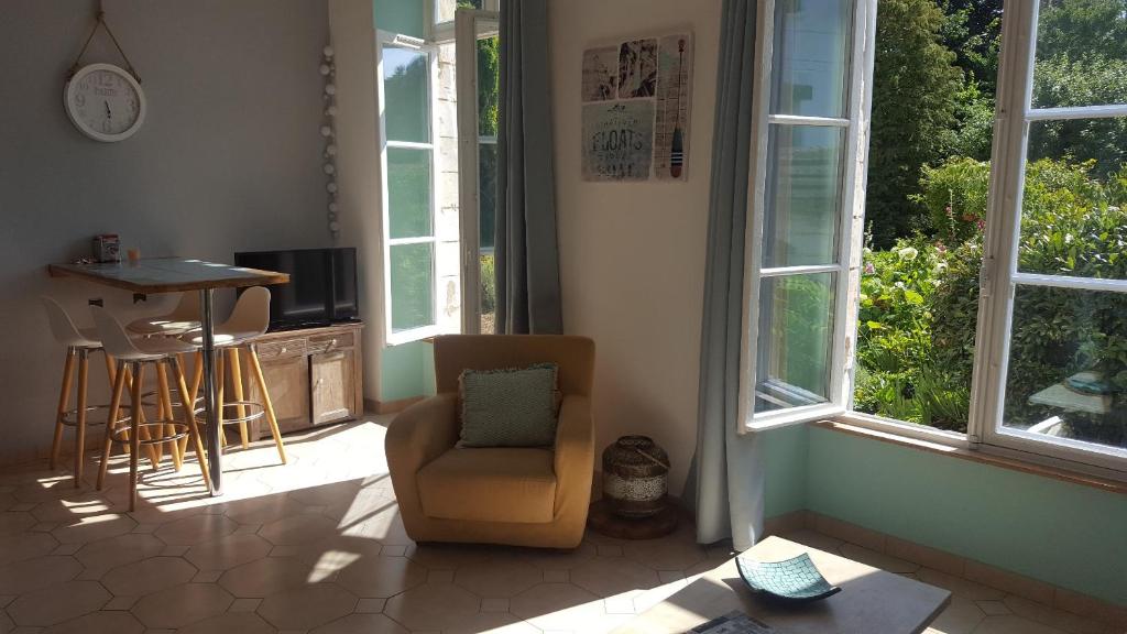 a living room with a chair and a table and windows at Appartement dans maison de charme Doullens in Doullens