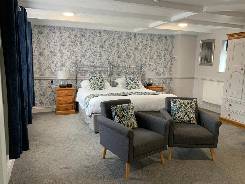 a bedroom with a large bed and two chairs at The Red Lion Inn in Spilsby