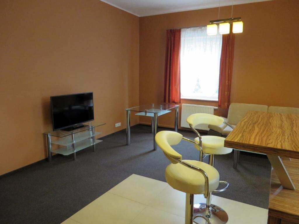 sala de estar con mesa, sillas y TV en City Apartments Protos, en Knurów