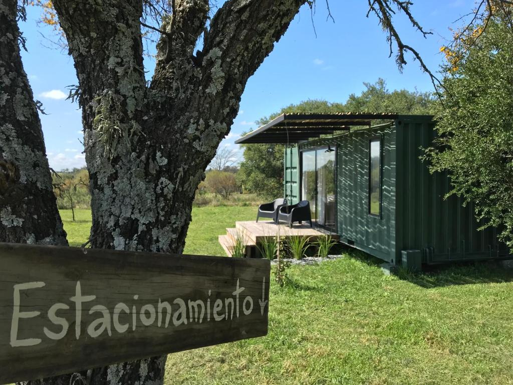 a green tiny house sitting next to a tree at Chacra La Recompensa Glamtainer in Paysandú
