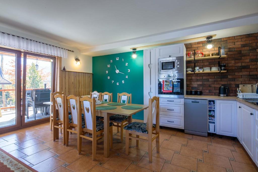 uma cozinha com uma mesa e cadeiras e uma parede verde em Pokoje gościnne Borowy em Kościelisko