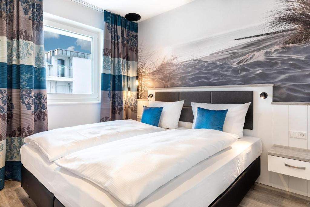 een slaapkamer met een groot wit bed met blauwe kussens bij Meerblickvilla Großenbrode in Großenbrode