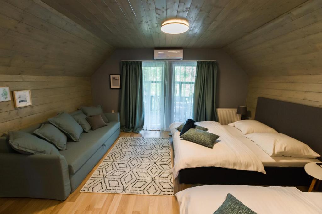 sypialnia z 2 łóżkami, kanapą i oknem w obiekcie Lubi Lodge w mieście Balatonboglár