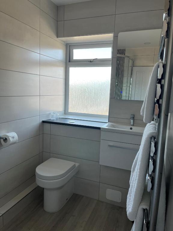 a white bathroom with a toilet and a window at The Pines Hotel in Swanage