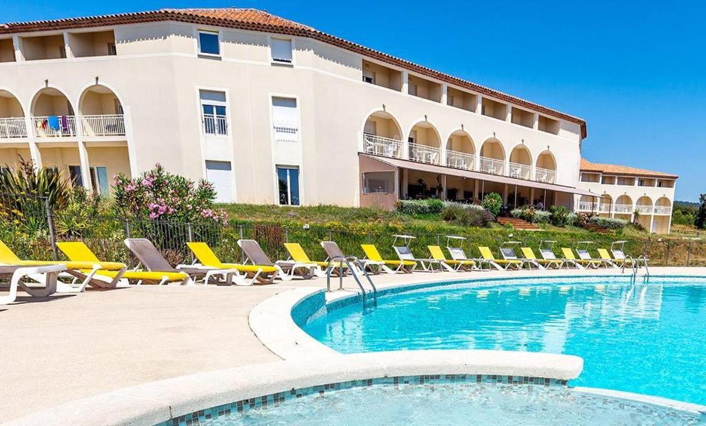 un hôtel avec une piscine, des chaises et un bâtiment dans l'établissement Très bel appartement spacieux, à Signes