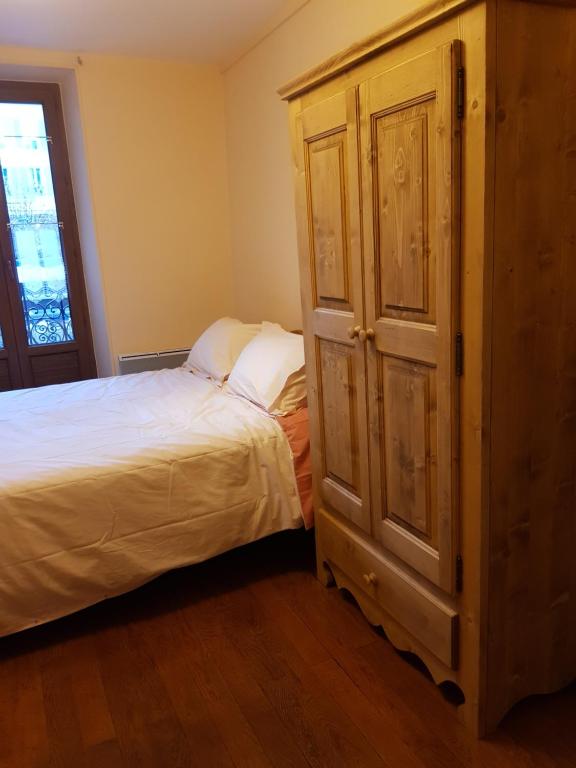 a bedroom with a bed and a wooden cabinet at Barcelonnette studio 2 personnes in Barcelonnette