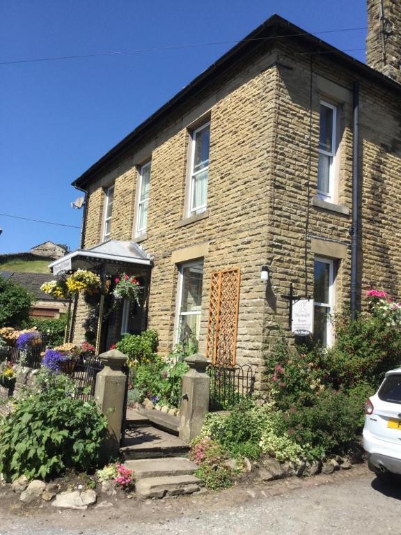 a brick house with flowers in front of it at Thornsgill House Bed & Breakfast in Askrigg