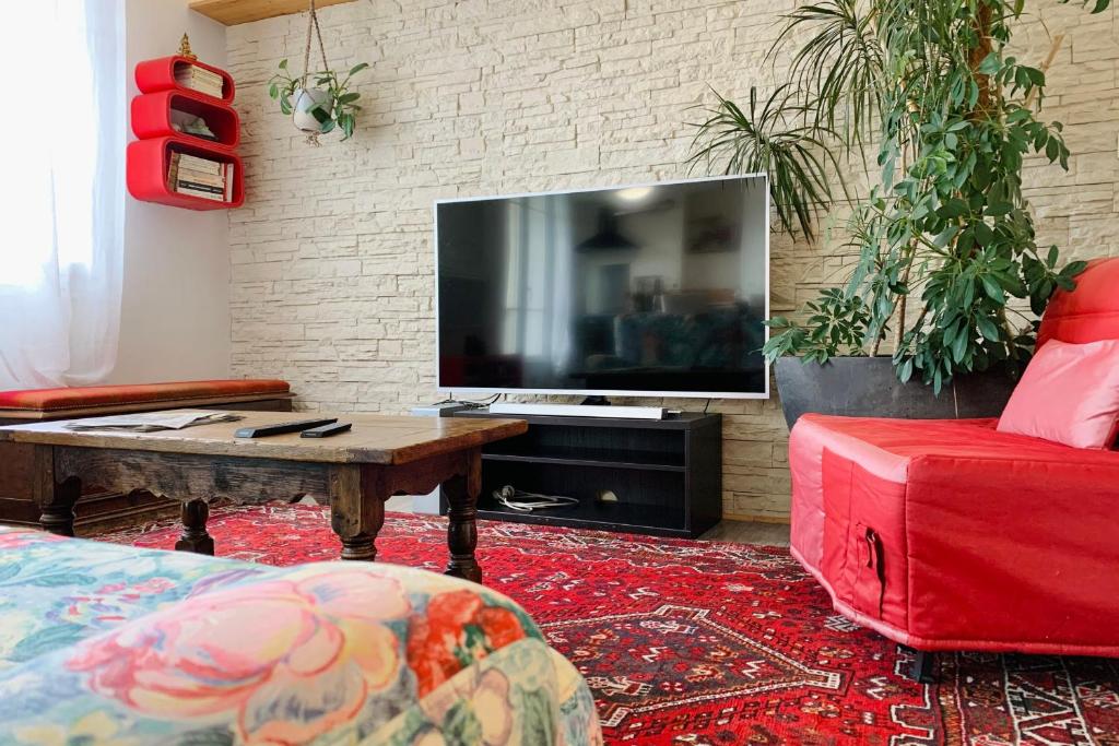 - un salon avec une grande télévision et un canapé rouge dans l'établissement #1A - Le Bouquet, à Grenoble