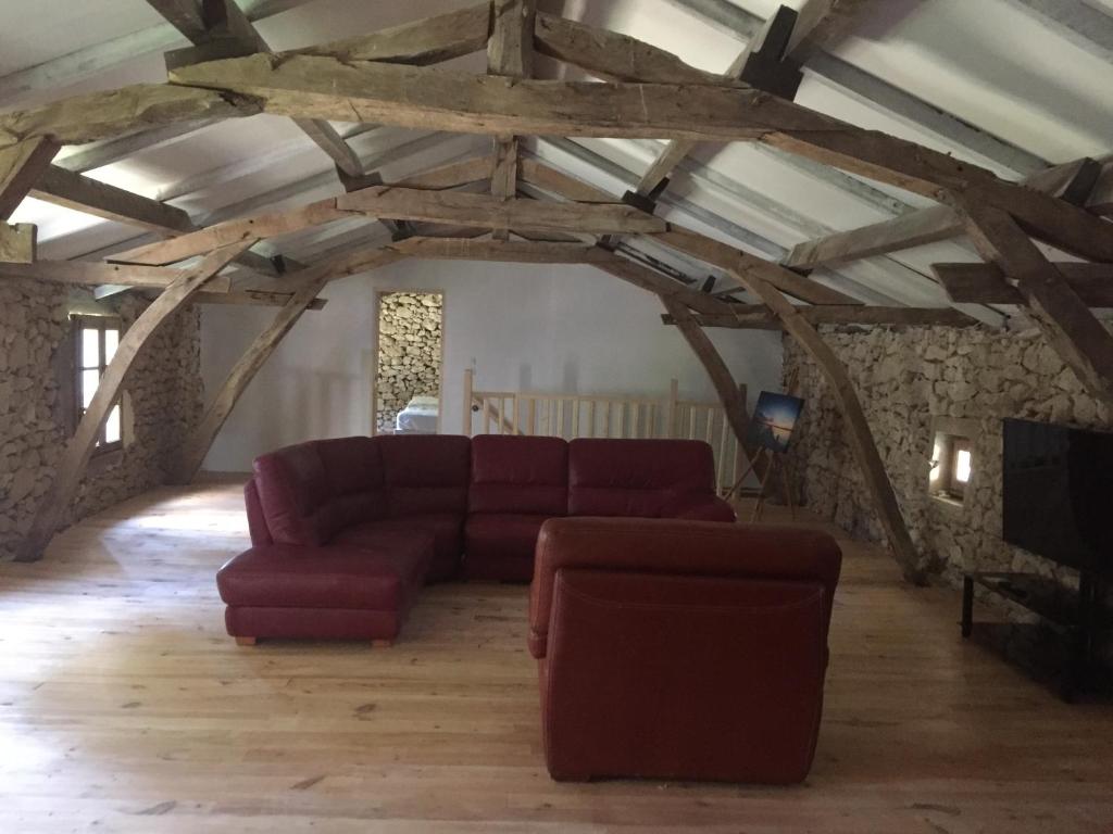 a living room with a red couch and a tv at La Sabatière in Bergerac