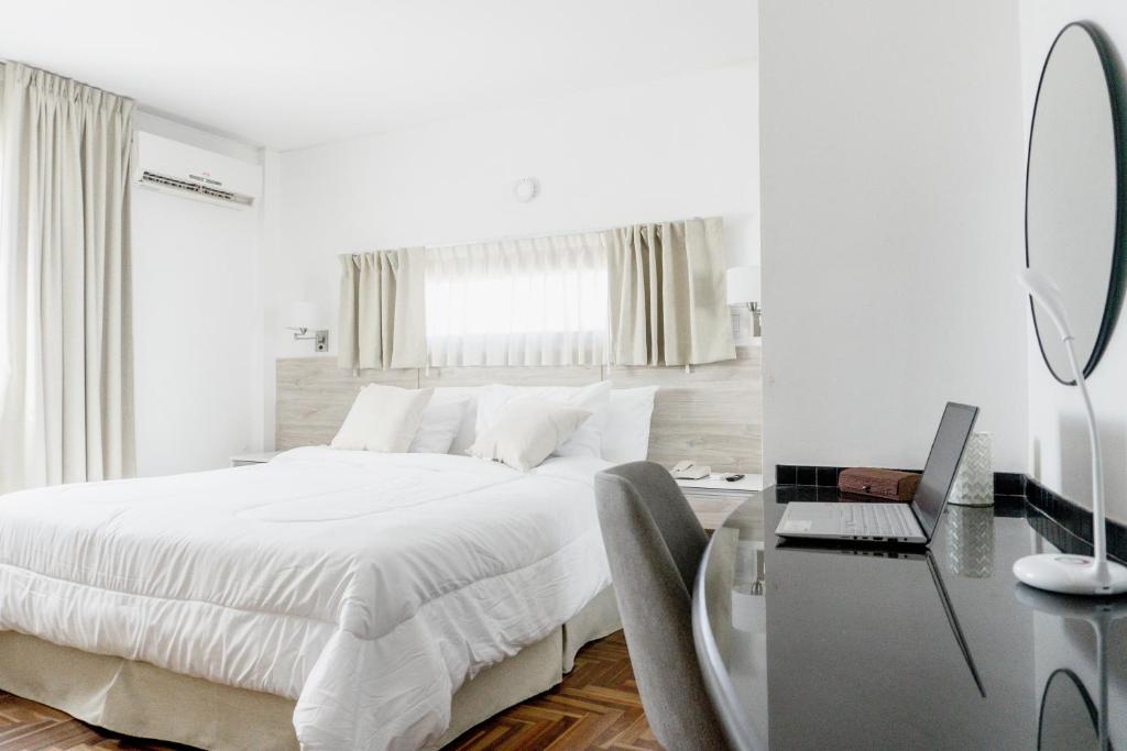 a white bedroom with a bed and a desk with a mirror at Mediterráneo Hotel y Spa in Rosario