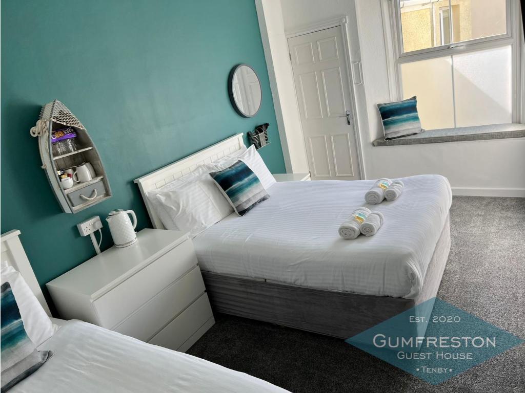Gumfreston Guest House في تينبي: سريرين في غرفة بجدران زرقاء