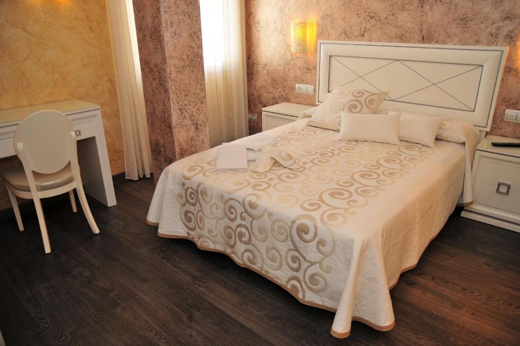 a bedroom with a bed and a table and a chair at Hostal Rabel in Ponferrada