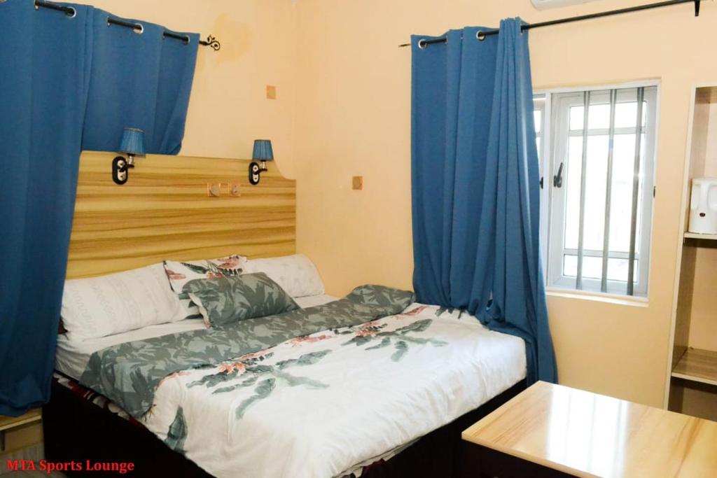 a bedroom with a bed with blue curtains at MTA Lounge and Leisures in Enugu