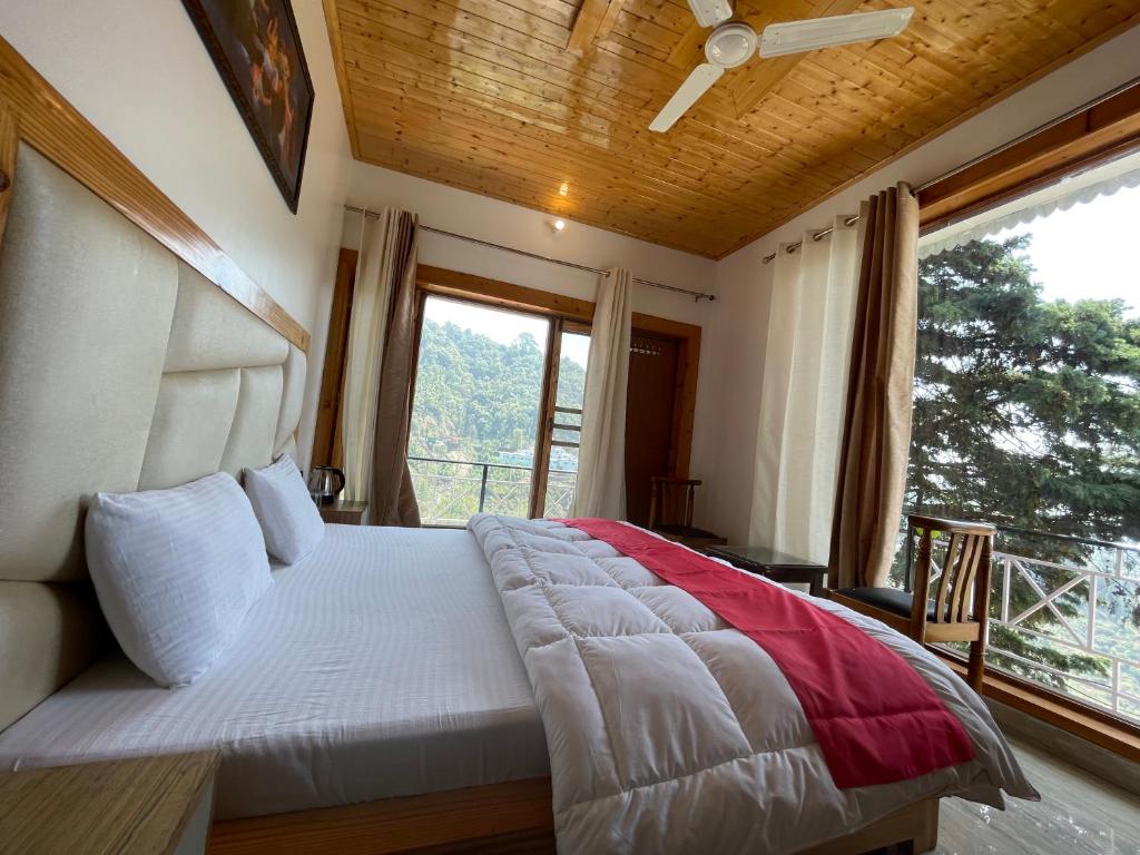 a bedroom with a large bed with a large window at Hotel Himalayan Village in Mussoorie