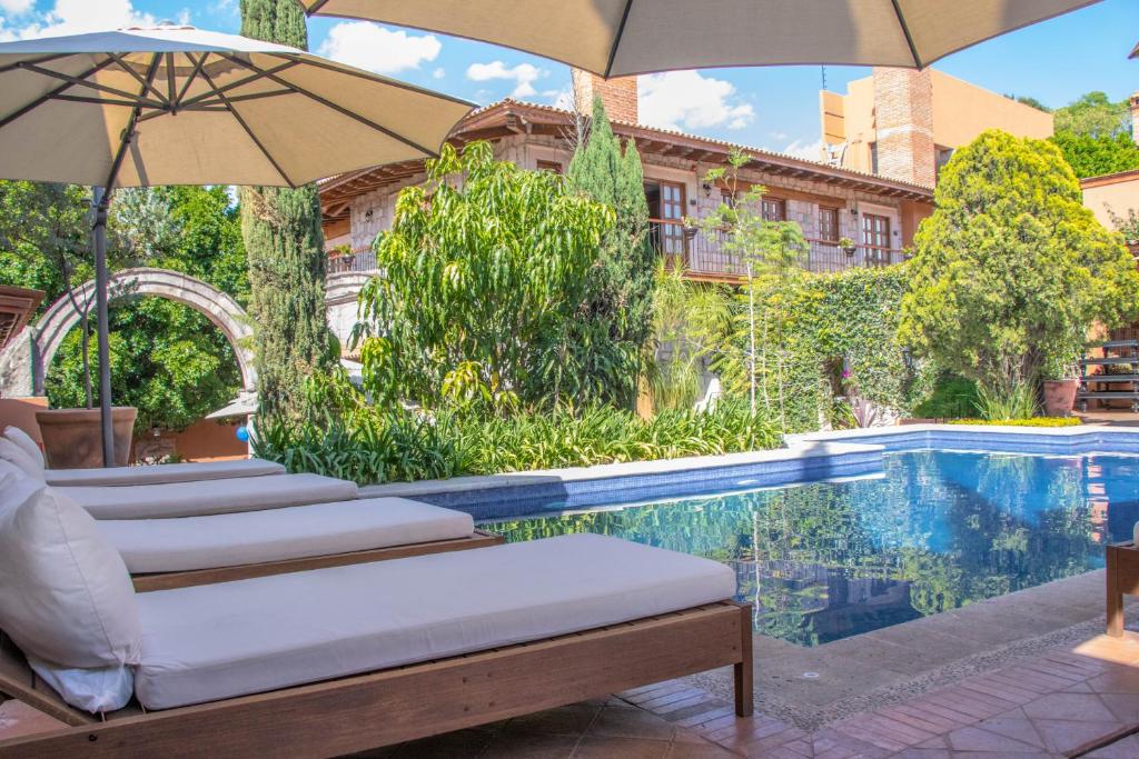 モレリアにあるGamma Morelia Vista Bellaのスイミングプールのそばのラウンジチェア(パラソル付)