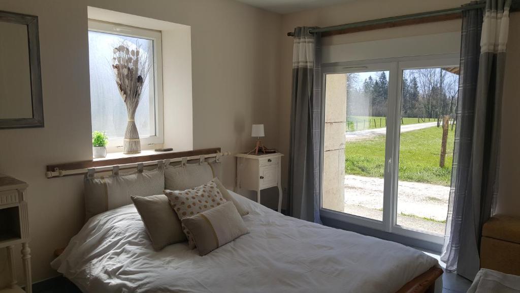 Un dormitorio con una cama blanca con una ventana. en Gites des Casernes, en Saint-Christophe