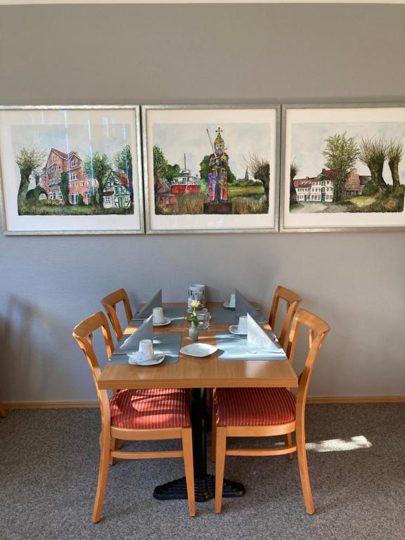 a dining room table with chairs and paintings on the wall at Hotel Diamant in Wedel