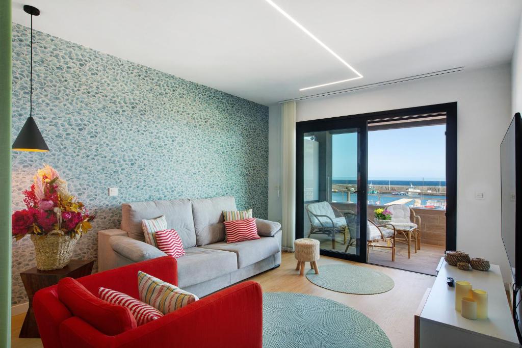 a living room with a couch and red chairs at La Casita del Muelle in Melenara