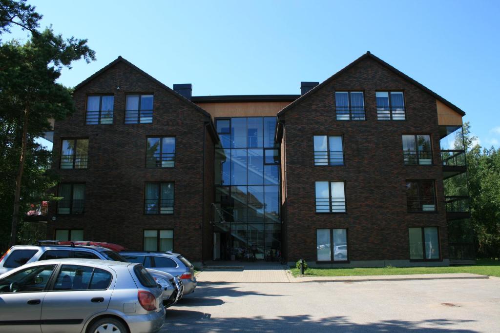 a large brick building with cars parked in a parking lot at Kotkapoja Residence in Kuressaare