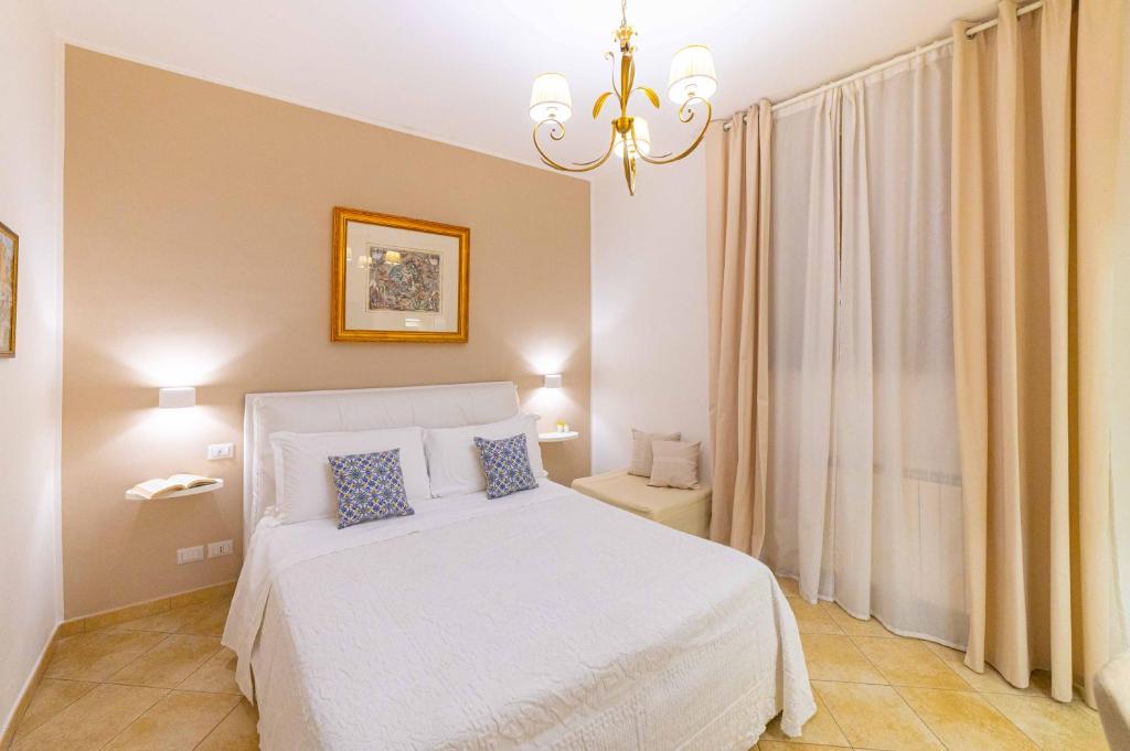 a bedroom with a white bed and a chandelier at Bed and Breakfast Dionisio in Taormina